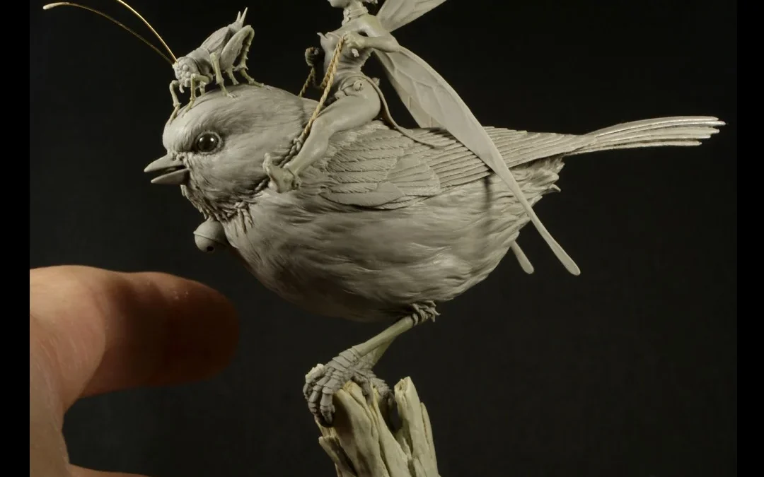 Hand holding a detailed bird sculpture with spread wings, open beak
