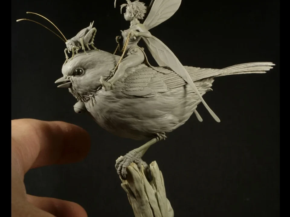 Hand holding a detailed bird sculpture with spread wings, open beak