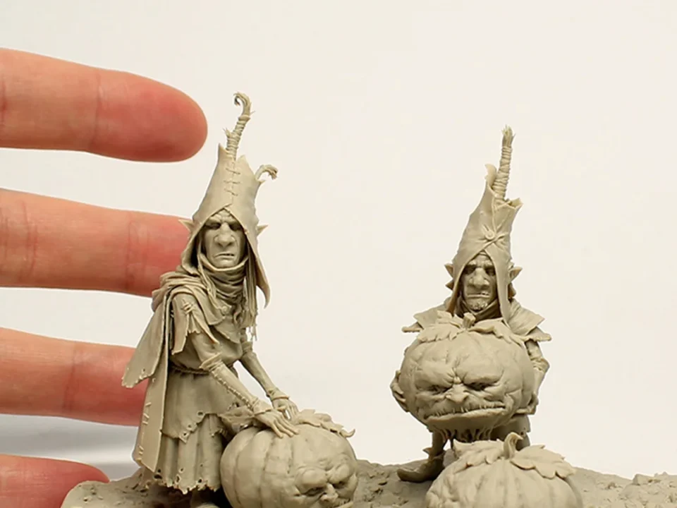 Handheld miniature witch figurine with a pumpkin, pointed hat, cloak, and staff, crafted for Black Sun miniatures
