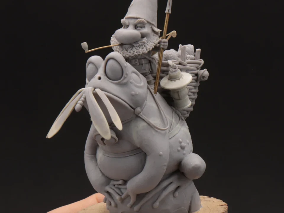 Hand holding a small figurine of a man in a hat and armor, labeled 'Sculpthed Blacksmith miniature'
