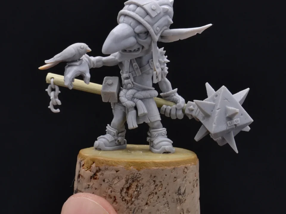 Miniature figure of a helmeted warrior with a sword and bird perched on shoulder, standing on a rock