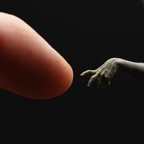 Close-up of a hand extending toward a red, vein-like sculpture against black background