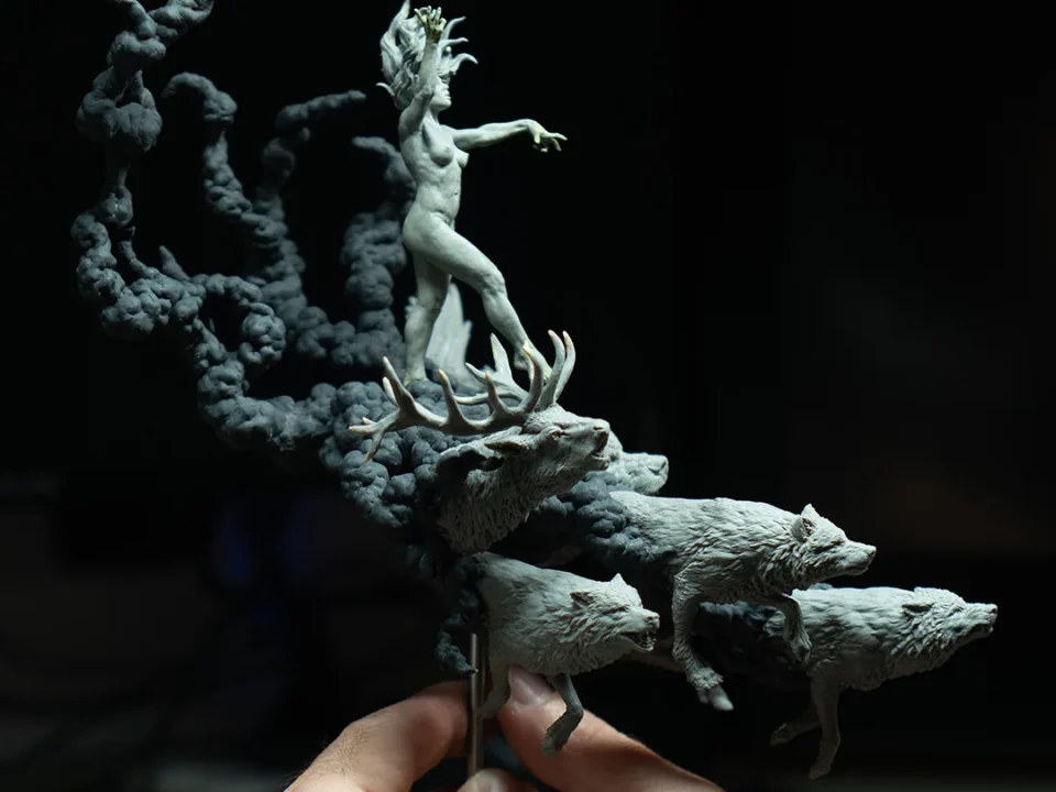 Person holding a sculpted human figure in a dark room with animals in the background