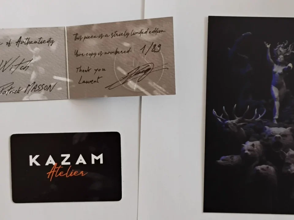 Three artist cards with 'Kazam Helier' signatures arranged in a triangular formation on a white wall